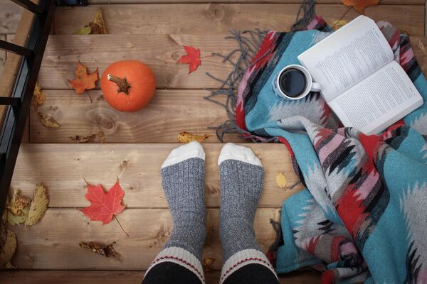 A person wearing grey socks, with a book and a pumpkin